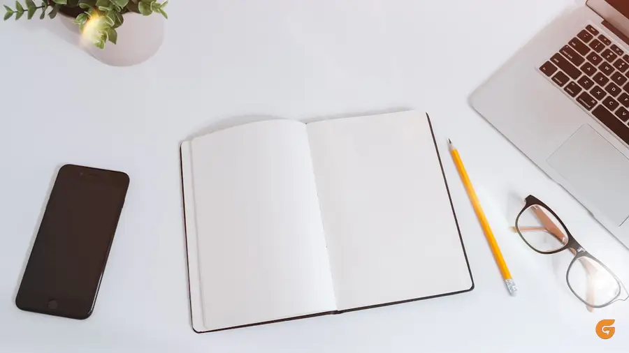 Writing in a notebook beside a laptop